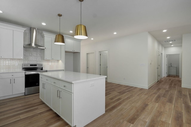 kitchen with wall chimney range hood, pendant lighting, a kitchen island, stainless steel range with electric cooktop, and white cabinets