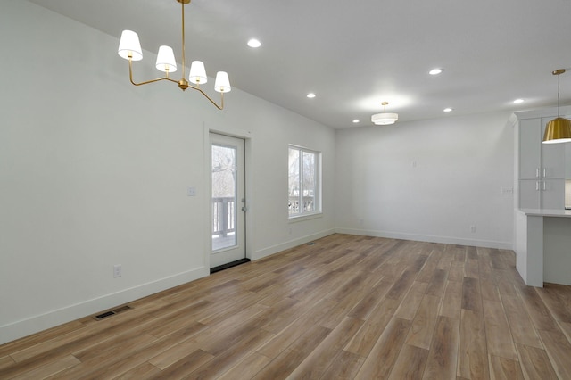 spare room with light wood-type flooring and an inviting chandelier