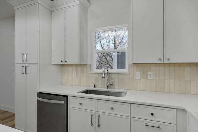 kitchen with tasteful backsplash, dishwasher, light stone countertops, white cabinets, and sink