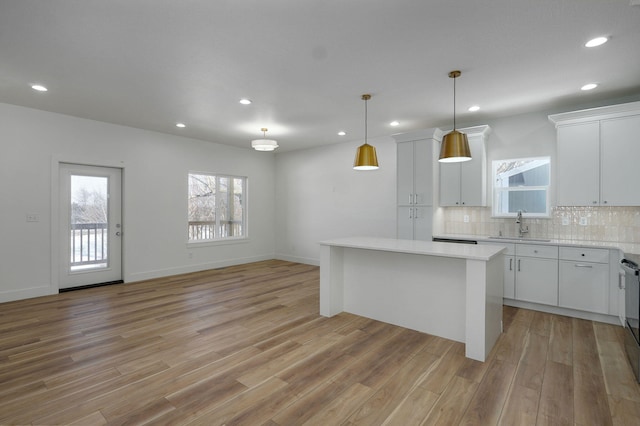 kitchen featuring a kitchen island, white cabinetry, backsplash, hanging light fixtures, and light wood-type flooring