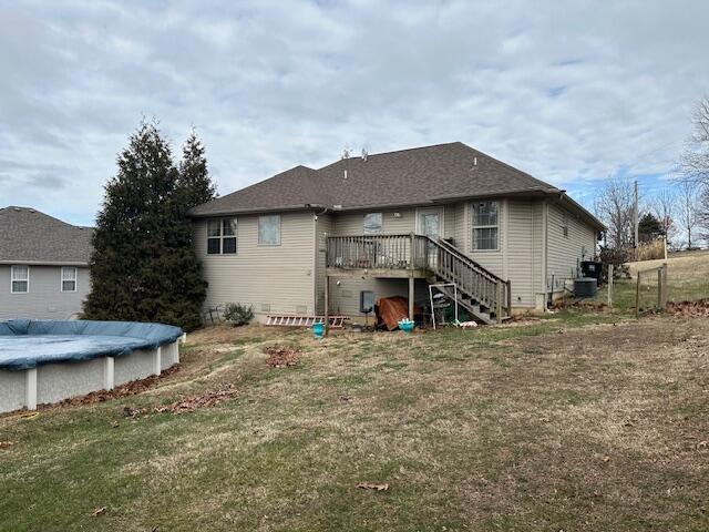 rear view of property featuring a lawn and a swimming pool side deck