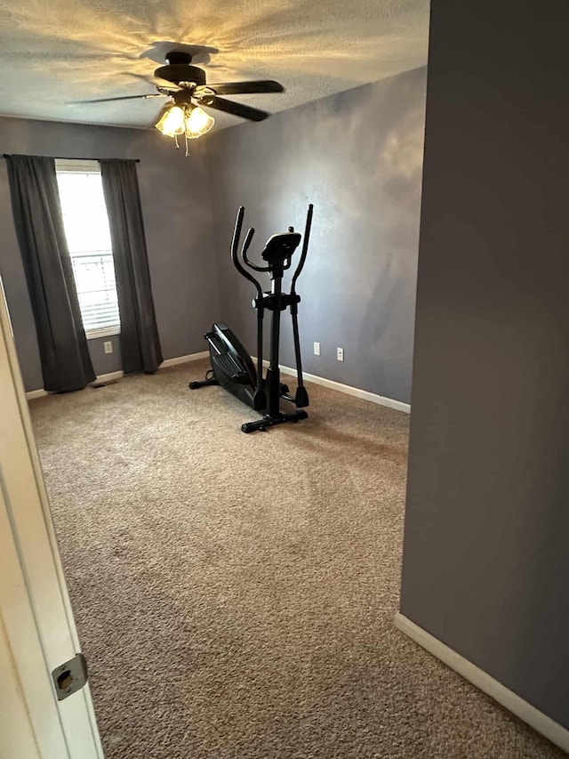 workout room featuring ceiling fan, carpet, and a textured ceiling