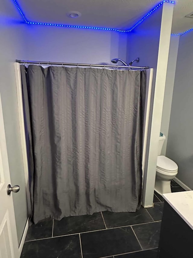 bathroom with tile patterned floors, vanity, toilet, and curtained shower