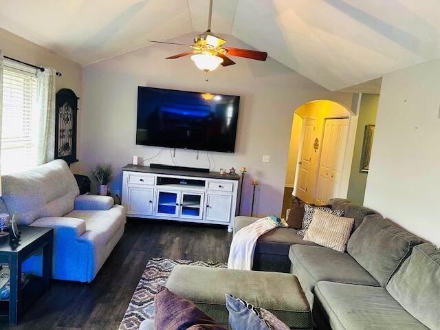 living room with ceiling fan, dark hardwood / wood-style floors, and vaulted ceiling