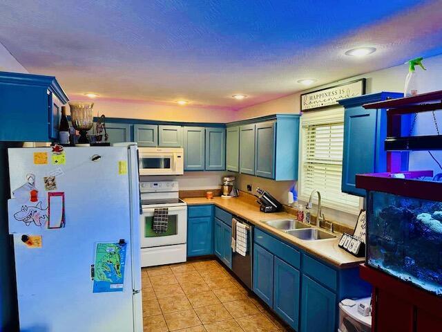 kitchen with blue cabinetry, sink, light tile patterned floors, and white appliances