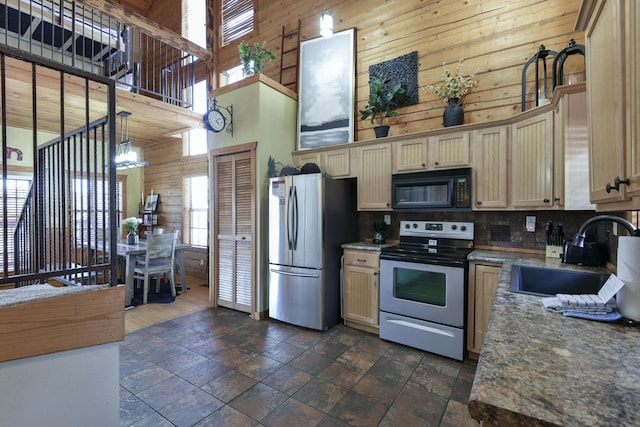 kitchen featuring appliances with stainless steel finishes, decorative backsplash, a towering ceiling, pendant lighting, and sink