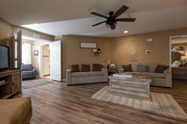 living room featuring ceiling fan and dark hardwood / wood-style flooring