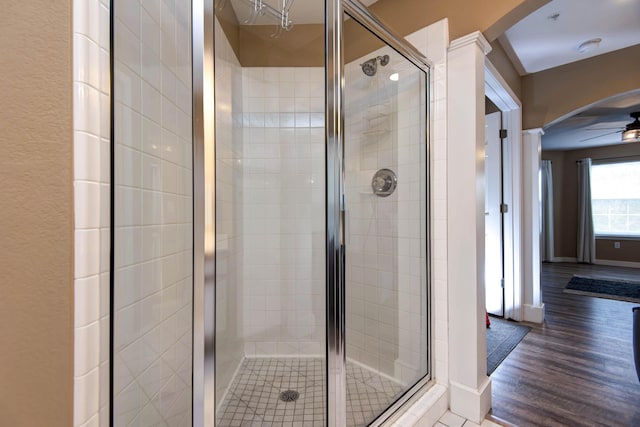 bathroom featuring ceiling fan, wood-type flooring, and a shower with door