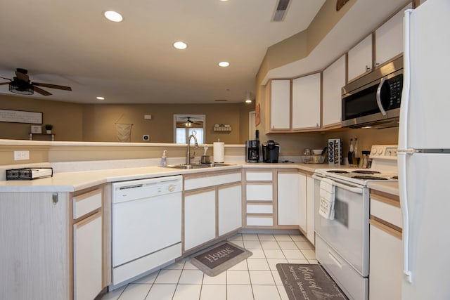 kitchen with kitchen peninsula, sink, white appliances, white cabinetry, and light tile patterned flooring