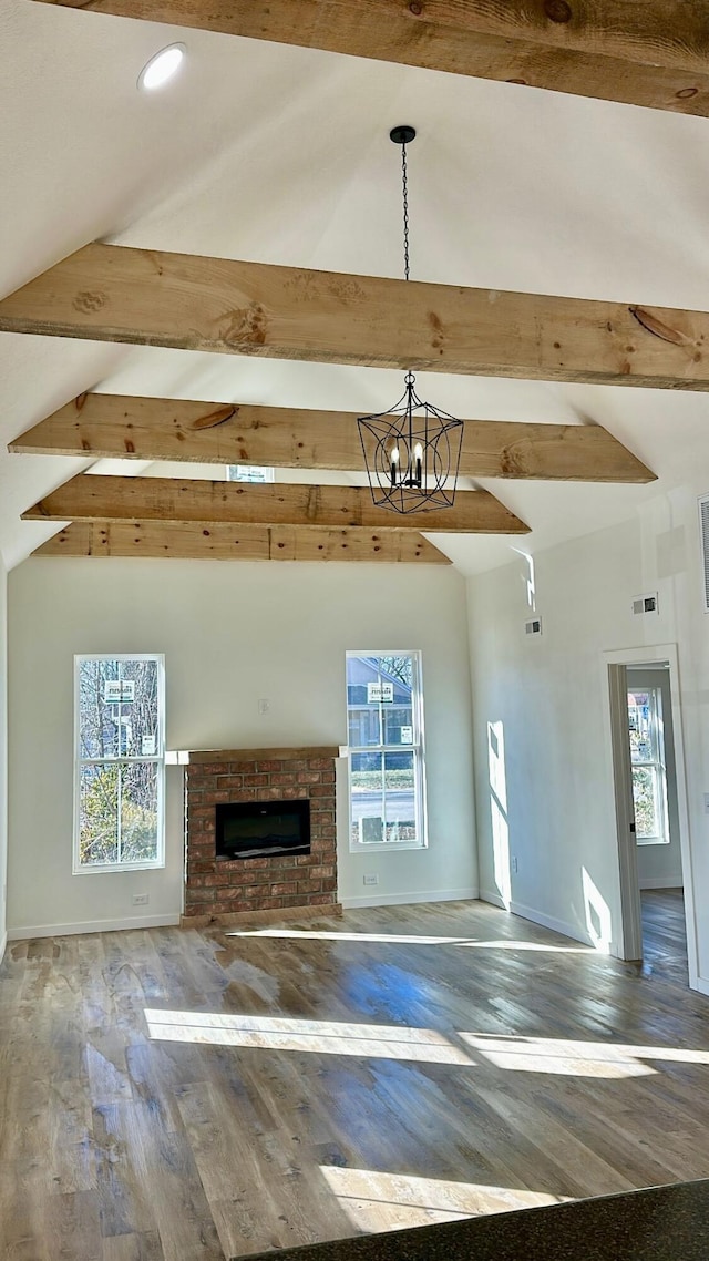 unfurnished living room with hardwood / wood-style floors, a fireplace, a chandelier, high vaulted ceiling, and beam ceiling