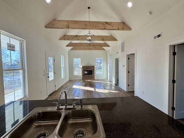 kitchen featuring decorative light fixtures, a notable chandelier, sink, beamed ceiling, and hardwood / wood-style flooring