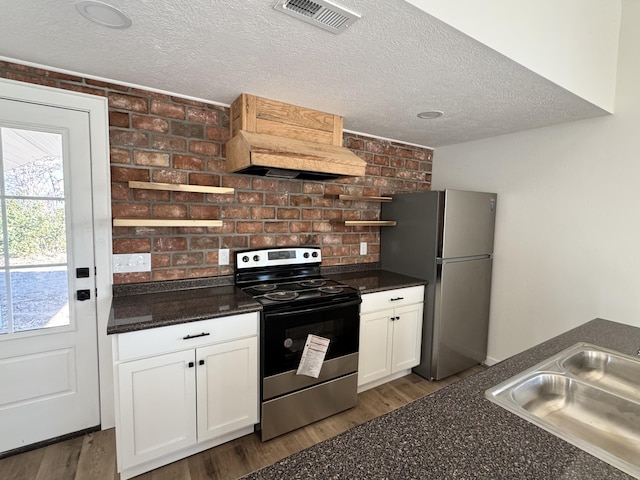 kitchen featuring brick wall, white cabinets, appliances with stainless steel finishes, sink, and custom range hood