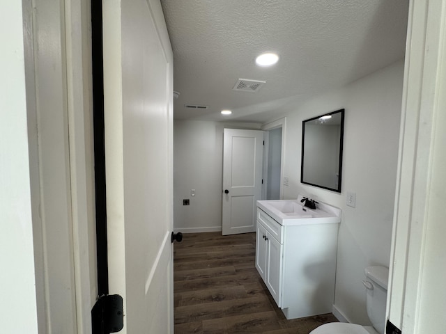 bathroom with toilet, vanity, a textured ceiling, and hardwood / wood-style floors