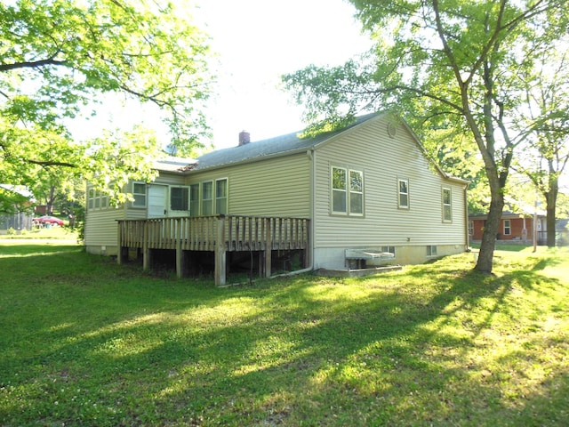 rear view of house featuring a wooden deck and a lawn