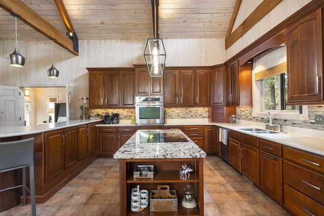 kitchen featuring decorative light fixtures, sink, stainless steel appliances, and a kitchen island