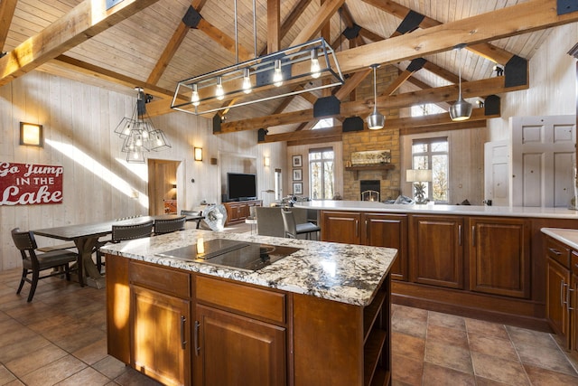 kitchen featuring black electric stovetop, a kitchen island, a fireplace, and hanging light fixtures