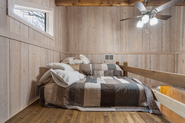 bedroom featuring ceiling fan, hardwood / wood-style flooring, and wooden walls