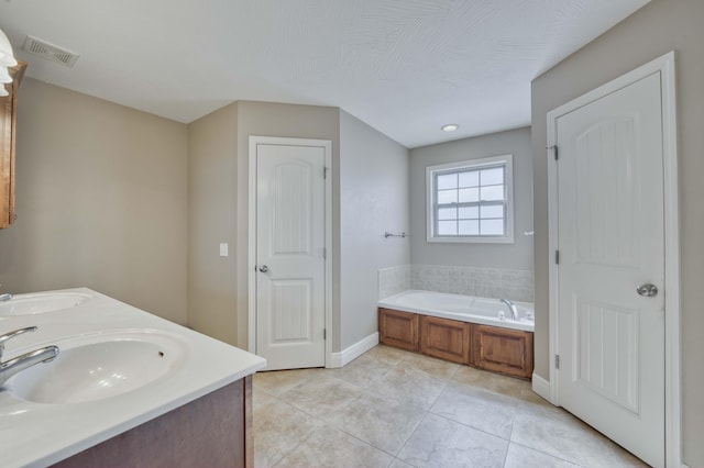 bathroom with a textured ceiling, a bath, vanity, and tile patterned flooring