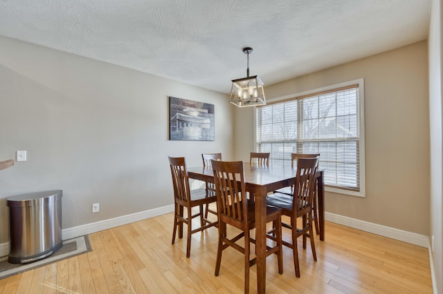 dining space with a textured ceiling, a chandelier, and light hardwood / wood-style flooring