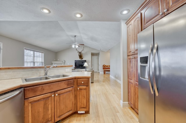 kitchen featuring appliances with stainless steel finishes, sink, vaulted ceiling, ceiling fan, and light hardwood / wood-style flooring