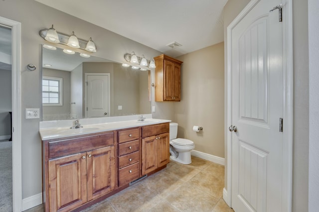 bathroom with toilet, vanity, and tile patterned flooring