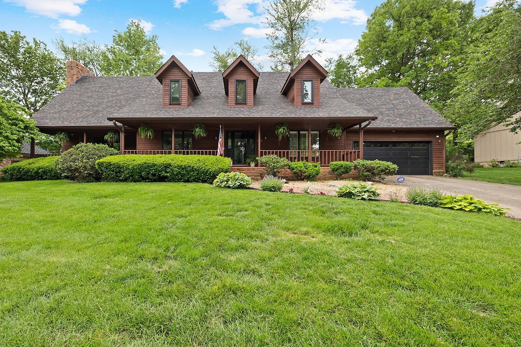 view of front of house with covered porch, a garage, and a front lawn