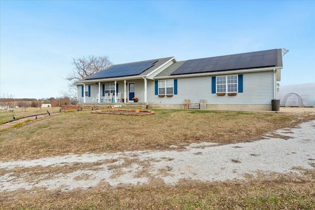 single story home featuring covered porch, a front yard, and solar panels