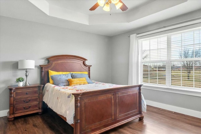 bedroom featuring ceiling fan, dark hardwood / wood-style flooring, and a raised ceiling