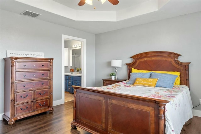 bedroom with ensuite bathroom, ceiling fan, dark hardwood / wood-style floors, a raised ceiling, and sink