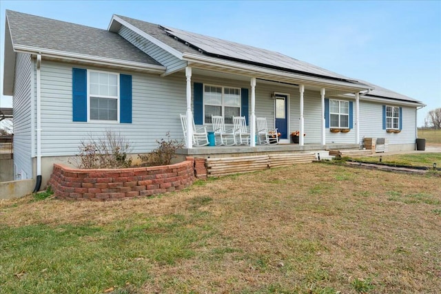 ranch-style home with covered porch, solar panels, and a front lawn