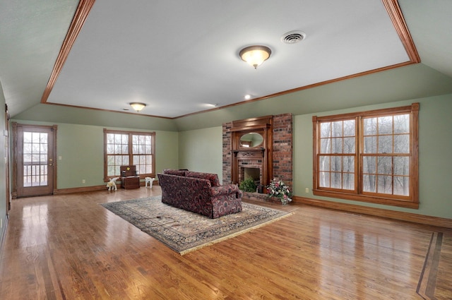 living room with lofted ceiling, crown molding, a fireplace, and light wood-type flooring