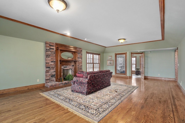 living room with a brick fireplace, crown molding, and hardwood / wood-style floors