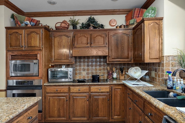 kitchen with backsplash, sink, crown molding, light stone countertops, and stainless steel appliances