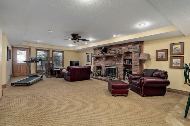 living room with a textured ceiling, ceiling fan, and a tray ceiling