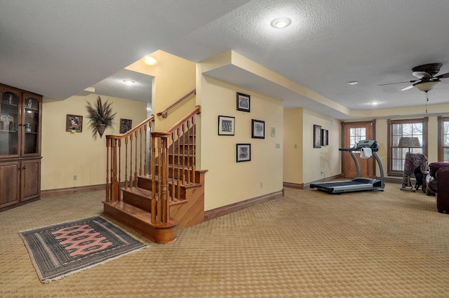 workout area with a textured ceiling, ceiling fan, and carpet floors