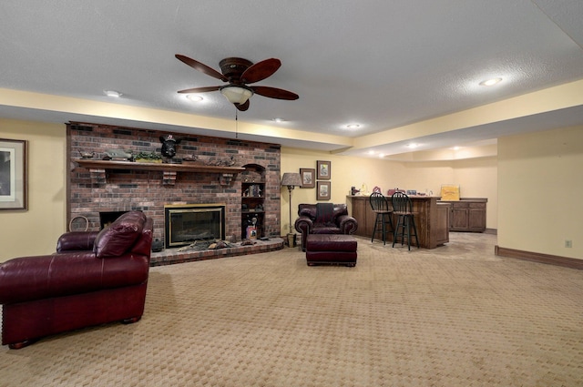 living room with a textured ceiling, light carpet, ceiling fan, a brick fireplace, and bar area