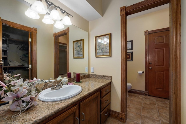 bathroom with toilet, vanity, and an inviting chandelier