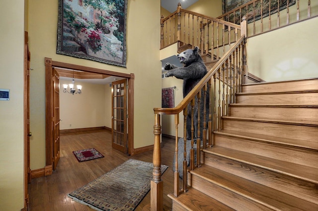 staircase featuring a high ceiling, hardwood / wood-style floors, and a notable chandelier