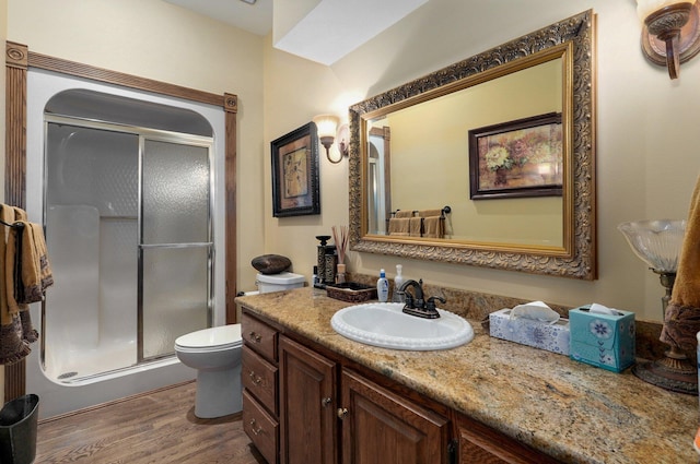 bathroom featuring an enclosed shower, vanity, toilet, and hardwood / wood-style flooring