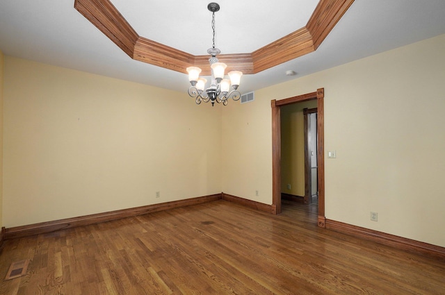 spare room with an inviting chandelier, ornamental molding, dark hardwood / wood-style flooring, and a raised ceiling