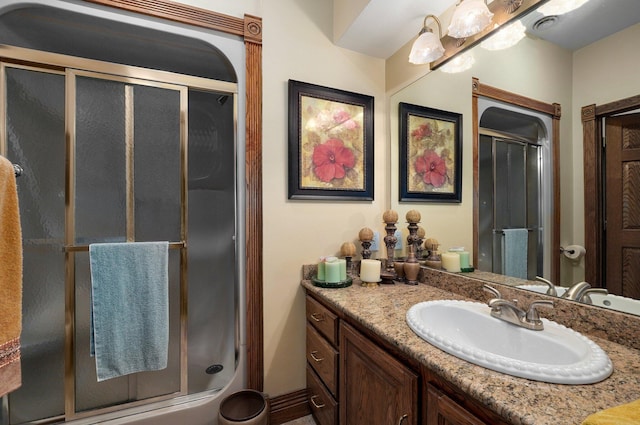 bathroom featuring a shower with shower door and vanity