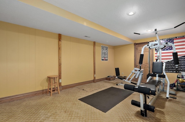 exercise area with a textured ceiling and carpet flooring