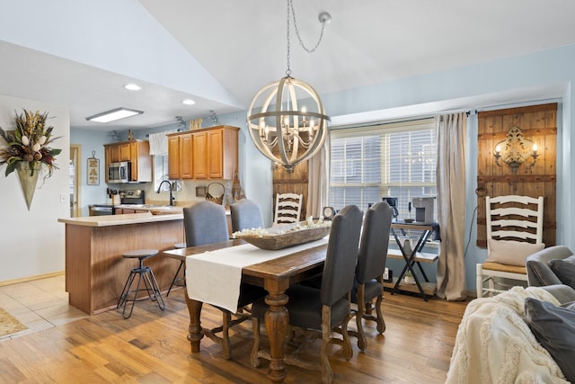 dining room with high vaulted ceiling, light wood-type flooring, a notable chandelier, and sink