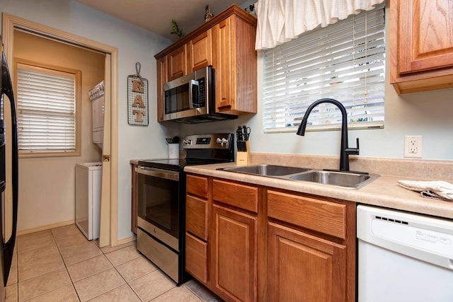 kitchen featuring stacked washer / dryer, sink, stainless steel appliances, and light tile patterned flooring