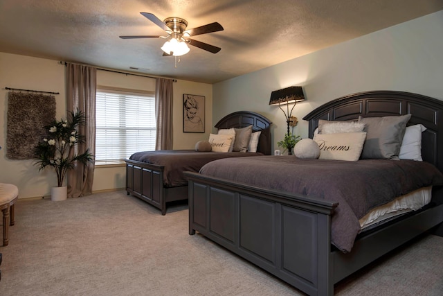 bedroom featuring light carpet, ceiling fan, and a textured ceiling