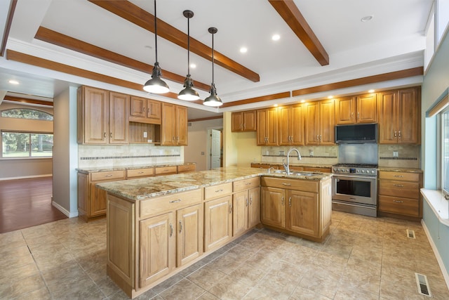 kitchen featuring light stone countertops, high end range, decorative light fixtures, an island with sink, and sink