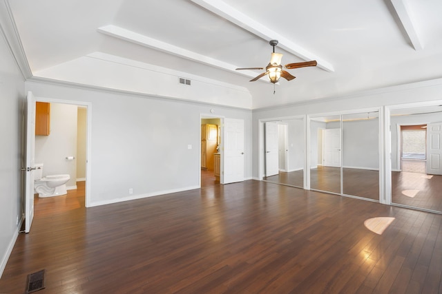 unfurnished bedroom featuring dark wood-type flooring, multiple closets, ceiling fan, and ensuite bath