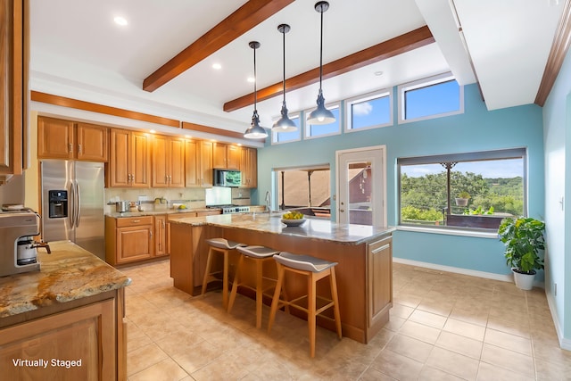 kitchen featuring appliances with stainless steel finishes, a center island, hanging light fixtures, and light stone countertops