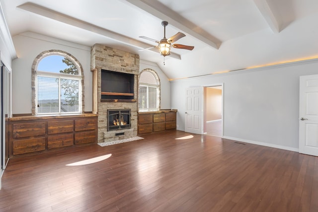 unfurnished living room with dark wood-type flooring, ceiling fan, a fireplace, and lofted ceiling with beams