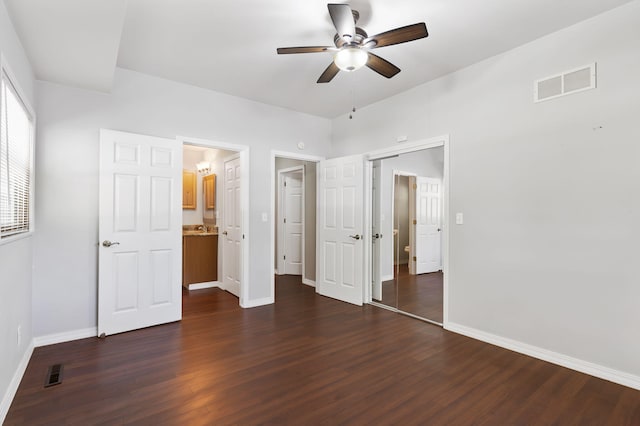 unfurnished bedroom with ceiling fan, dark wood-type flooring, ensuite bathroom, and a closet